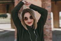 Дівчина в навушниках позує з піднятими руками — стокове фото