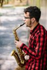 Saxophonist leaning on wall and playing sax — Stock Photo
