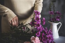 Середина жіночого флориста, що ріже ножицями букет квітів на столі — стокове фото