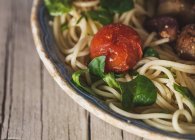 Nahaufnahme von Kirschtomaten und Basilikumblättern auf Teller mit Nudeln — Stockfoto