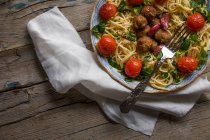 Ernte Bild von Pasta mit Frikadellen und Kirschtomaten auf Teller serviert auf Handtuch über Holztisch — Stockfoto