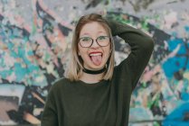 Blond girl in eyglasses putting tongue out — Stock Photo