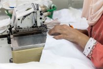 Обрезать женские руки с помощью швейной машинки — стоковое фото