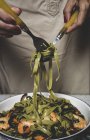 Cultivo femenino sinuoso tagliatelle verde italiano en tenedor - foto de stock