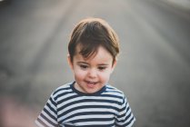 Портрет маленького хлопчика, який посміхається на асфальтній дорозі — стокове фото