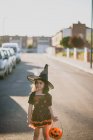 Girl in witch costume standing on street — Stock Photo