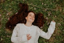 Dreamy girl lying on ground with blooming branch and smiling — Stock Photo