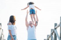 Man throwing girl in mid air at boardwalk — Stock Photo