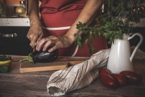 Couper les mains des cultures en tranches aubergines à bord — Photo de stock