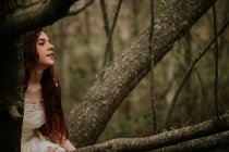 Мрійлива дівчина позує серед голих осінніх гілок — стокове фото