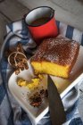 Натюрморт из лимонного торта на тарелке с коричными палочками и кружкой на полотенце — стоковое фото