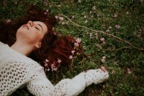 Dreamy girl lying on ground with blooming branch — Stock Photo