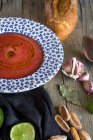 Sopa de tomate en plato estampado en mesa de madera con pan e ingredientes - foto de stock