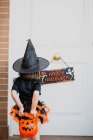 Menina em chapéu de bruxa na frente da porta — Fotografia de Stock