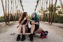 Девушки сидят на скейтборде и курят — стоковое фото