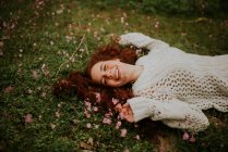 Мечтательная девушка лежит на земле с цветущими цветами — стоковое фото