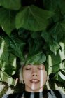 Girl lying on green leaves with eyes closed — Stock Photo