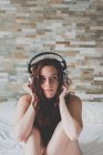 Girl sitting on bed and listening music — Stock Photo