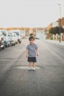 Menino posando na câmera enquanto estava de pé na estrada de asfalto em subúrbio — Fotografia de Stock