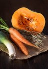 Primer plano de zanahorias frescas recogidas con hierba seca, puerro y calabaza - foto de stock