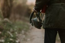 Imagen recortada de hombre sosteniendo máscara de gas en la mano y caminando por el camino rural - foto de stock