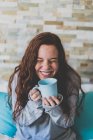 Girl holding blue mug and laughing — Stock Photo