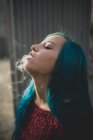 Portrait of blue haired teen girls smoking out at street scene — Stock Photo