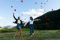 Women having fun with confetti at green meadow — Stock Photo