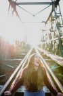 Дівчина сидить на залізничному мосту і сміється — стокове фото
