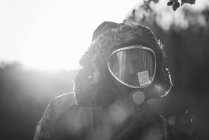 Portrait of man wearing coat hood and gas mask at countryside — Stock Photo