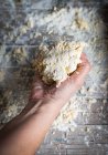 Sopra vista di mano con grumo di pasta su tavolo rustico con farina — Foto stock