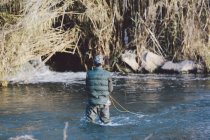 Visão traseira da pesca do pescador com haste no rio — Fotografia de Stock