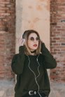 Дівчина в сонцезахисних окулярах регулює навушники — стокове фото