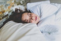 Femme sur oreiller au lit avec les yeux fermés — Photo de stock