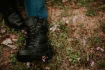 Piernas de las cosechas en jeans y botas contra hierba de otoño - foto de stock