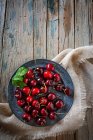 Diretamente acima vista de cerejas maduras em tigela na mesa rústica — Fotografia de Stock
