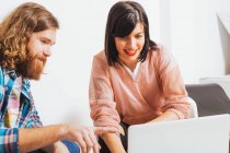 Dois jovens empresários da moda sorrindo e usando laptop enquanto discutem questões de negócios no local de trabalho. — Fotografia de Stock