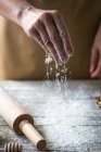 Close up view of hand pouring flour on rural wooden table — Stock Photo