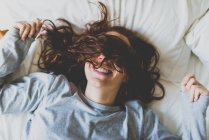 Дівчина лежить на ліжку з обличчям, покритим волоссям — стокове фото