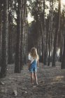 Vista posteriore della bambina bionda che posa nella foresta — Foto stock