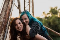 Mädchen befreit Freundin auf dem Rücken und schaut in die Kamera — Stockfoto