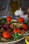 Espaguete e almôndegas decoradas com folhas de manjericão e tomates grelhados na travessa — Fotografia de Stock