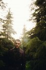 Портрет чоловіка в шкіряному пальто позує серед лісу і дивиться на камеру — стокове фото