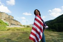 Pretty woman in USA flag posing at green valley — Stock Photo