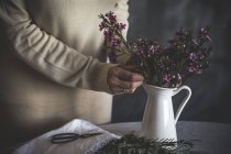 Sezione centrale di fiorista femminile che mette il fiore in vaso su tavolo — Foto stock