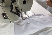 Vista de cerca de la máquina de coser con tela blanca - foto de stock