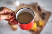Acima vista da mão feminina segurando xícara de chocolate quente sobre mesa turva — Fotografia de Stock