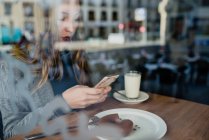 Girl using smartphone in beanery — Stock Photo