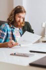 Portrait of bearded man working with blueprint at workplace in office. — Stock Photo