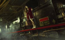 Молодая женщина стоит на большом черном поезде и держит перила . — стоковое фото